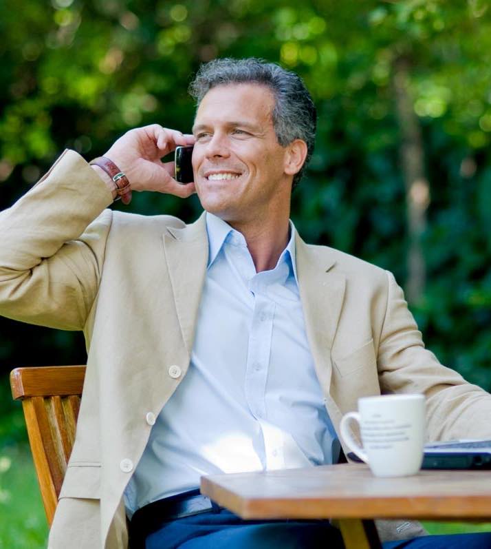 A businessman sitting outdoors talking on a mobile phone.